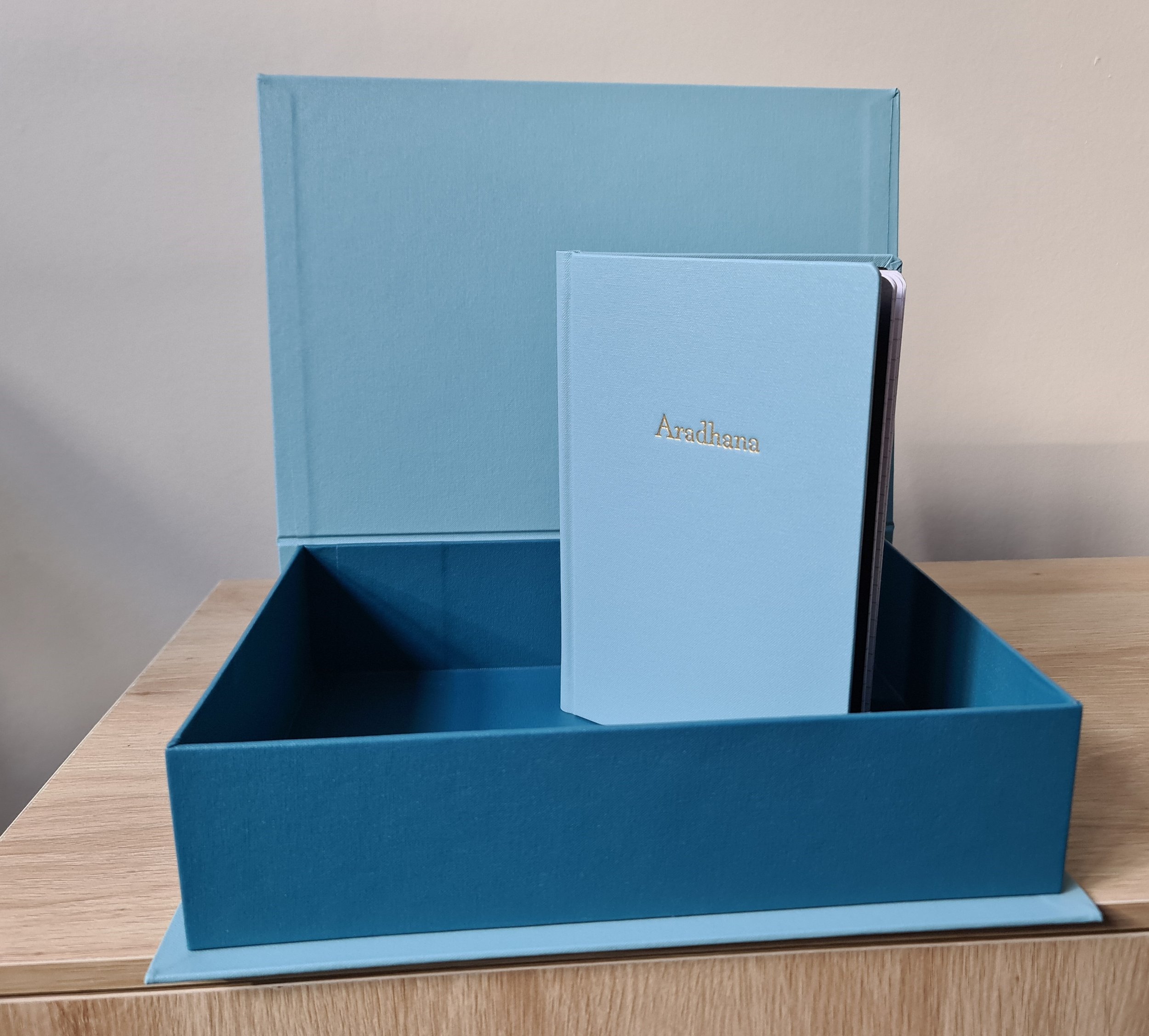 Blue box open on table with blue bound book standing inside